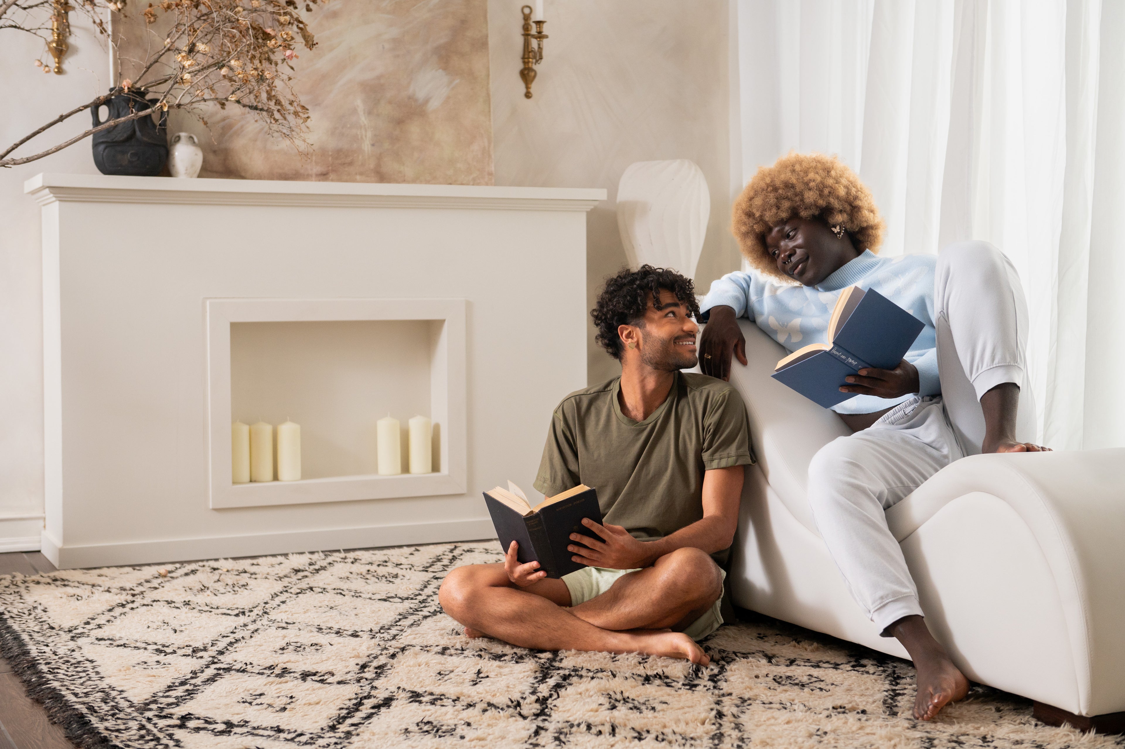 White IYKYK chaise in a living room with two models lounging and reading, enjoying each other's company